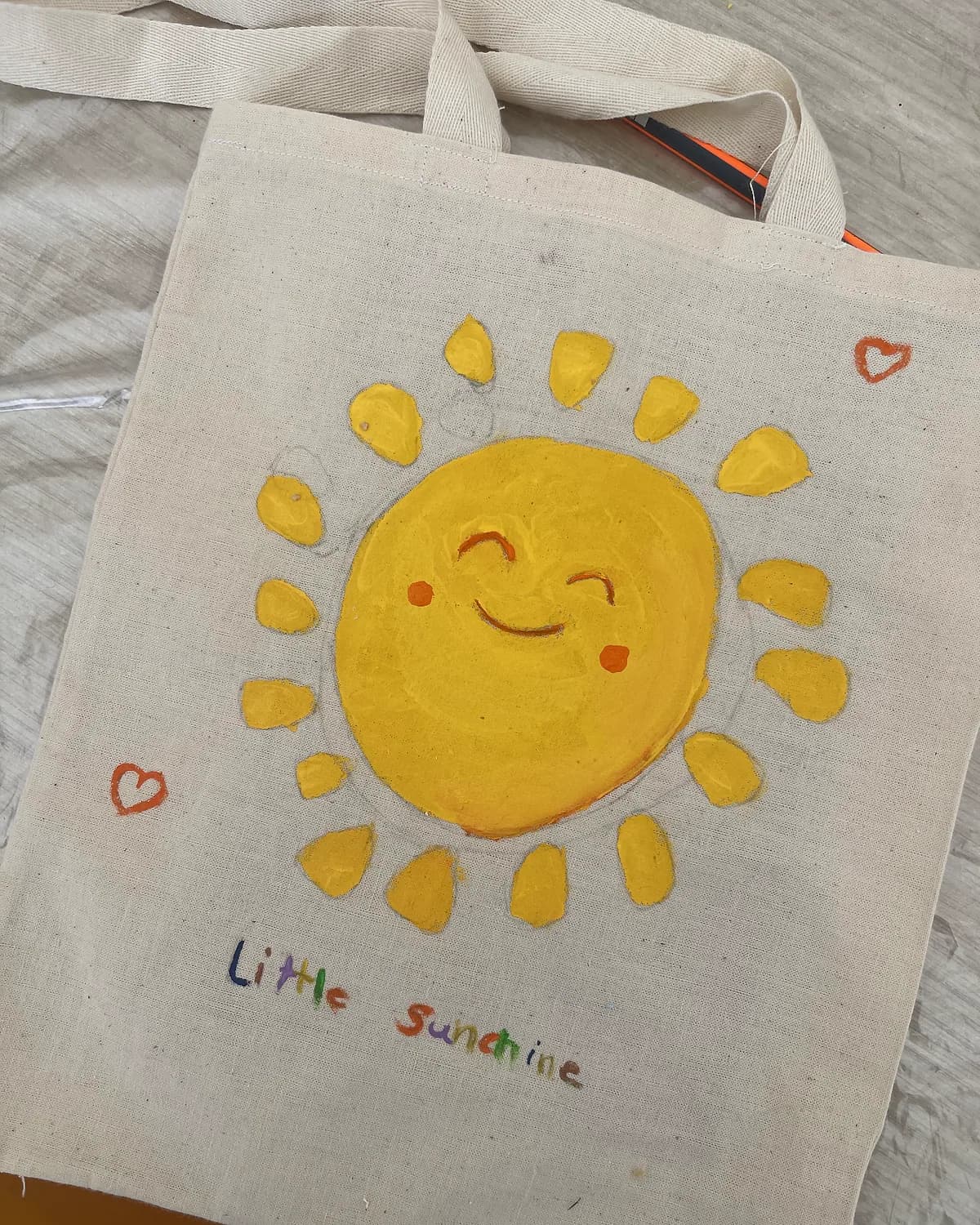 A tote bag hand-painted with a smiling sun
