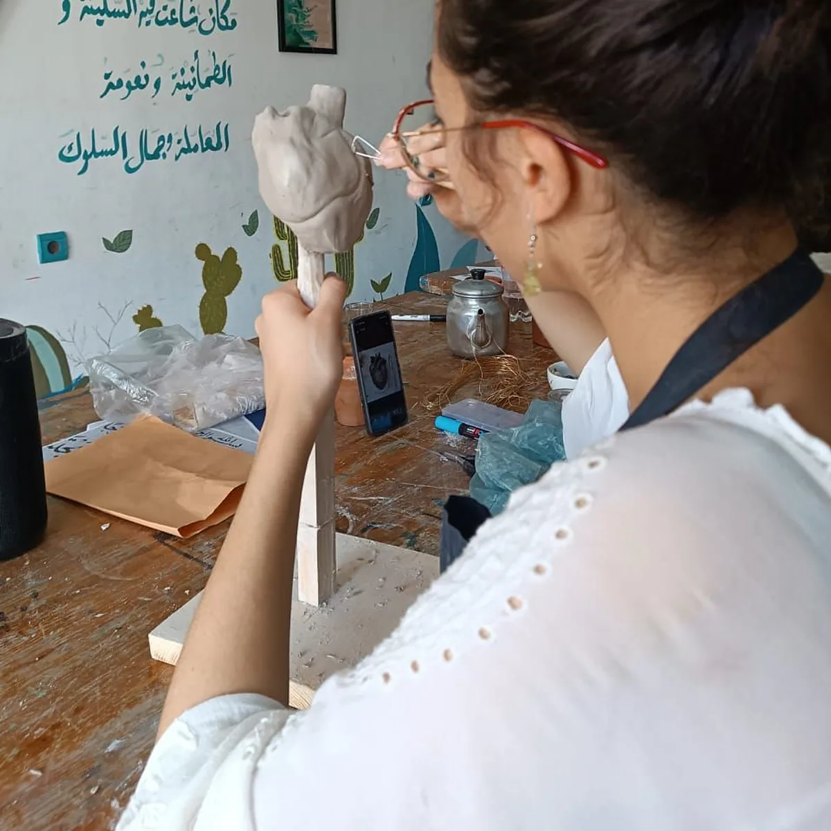 A student shaping a clay bust on a wooden armature – pottery and sculpture, arts plastiques class