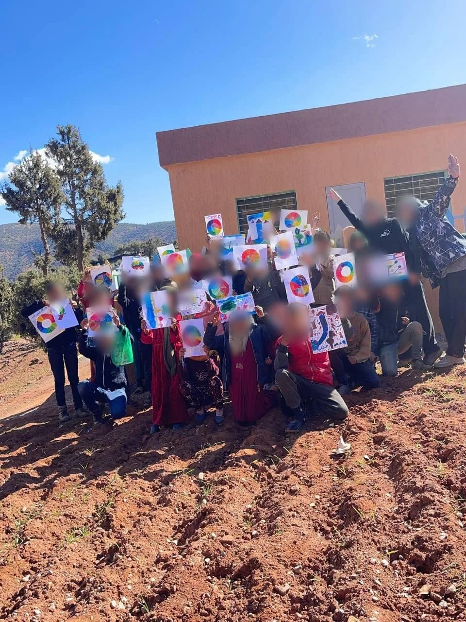 Children and two teachers holding up their colour-wheel paintings – kids visual arts (arts plastiques) workshop