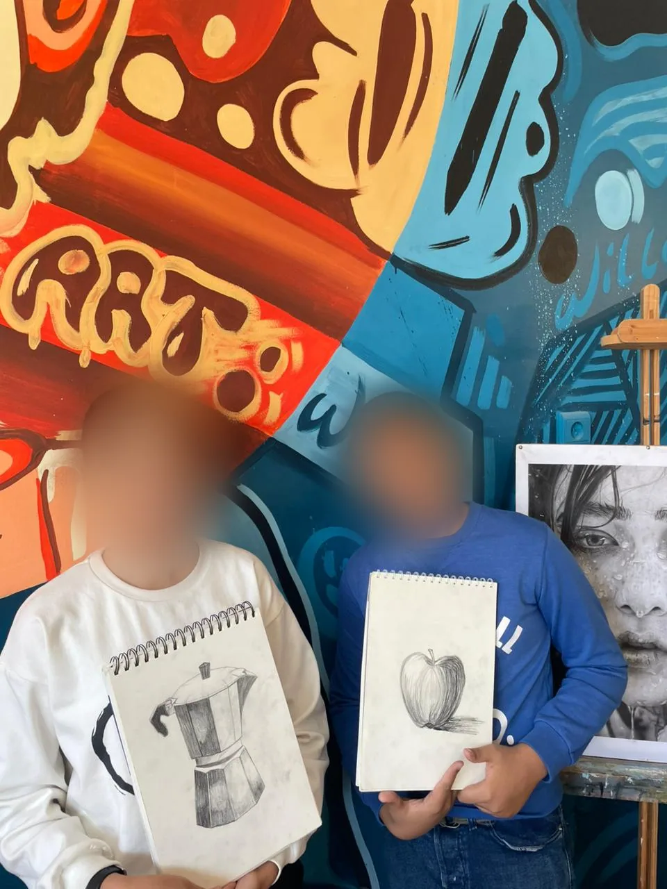 Two children showing their pencil sketches of a coffee pot and an apple – kids drawing class, arts plastiques in Casablanca & Fès