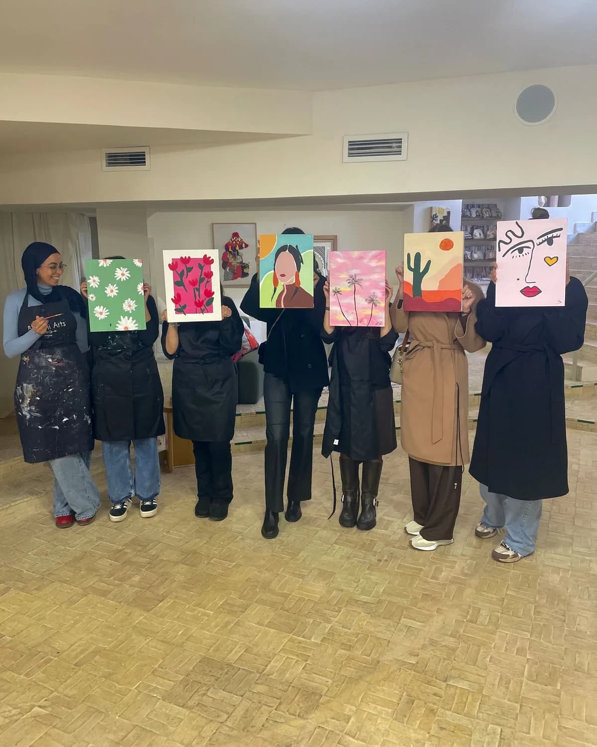 A group at Bluhimi Arts holding up their finished paintings